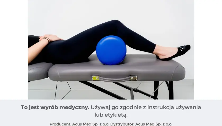 Osoba leży na kozetce, z niebieską piłką pod kolanami. To pomoc w ćwiczeniach na rwę kulszową.